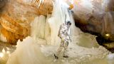 An analog astronaut in his space suit in the middle of big stalactites in a cave. He is part of the Mars analog mission in the Kaunertal glacier that took place in the year 2015.