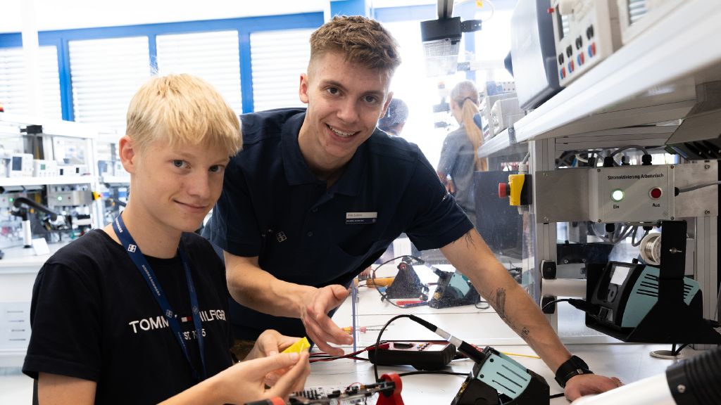 Schüler und Azubis löten in der Elektronikfertigung ein Radio.
