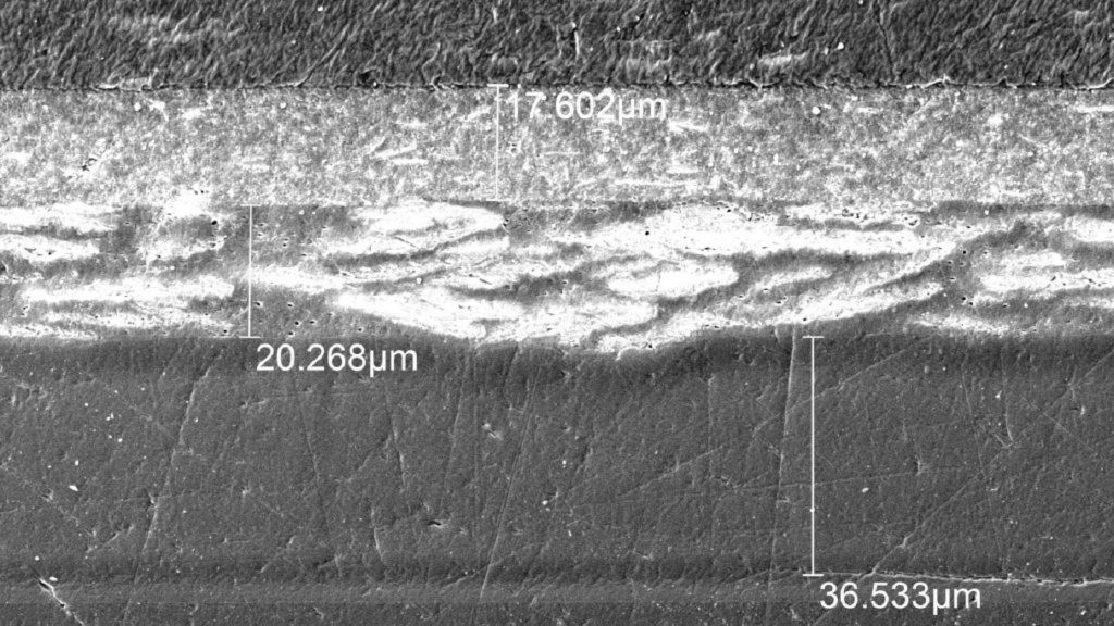 Fig. 1 : Micrographie montrant les différentes couches d'un échantillon de pare-choc automobile : matériau de base (PP), primaire, peinture, vernis (de haut en bas).